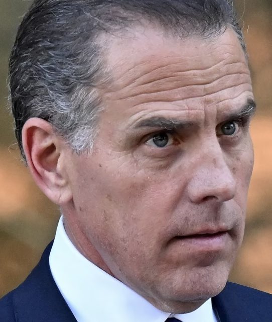 A close-up portrait shows a middle-aged man with short graying hair, wearing a dark suit jacket and white shirt, with a serious, focused expression as he looks off to the side. The image appears to relate to a post comparing the financial performance of "$LAPTOP" and "$TRUMP" tokens, suggesting the man pictured may be associated with the latter, though his identity is not confirmed by visible text or names in the image itself.