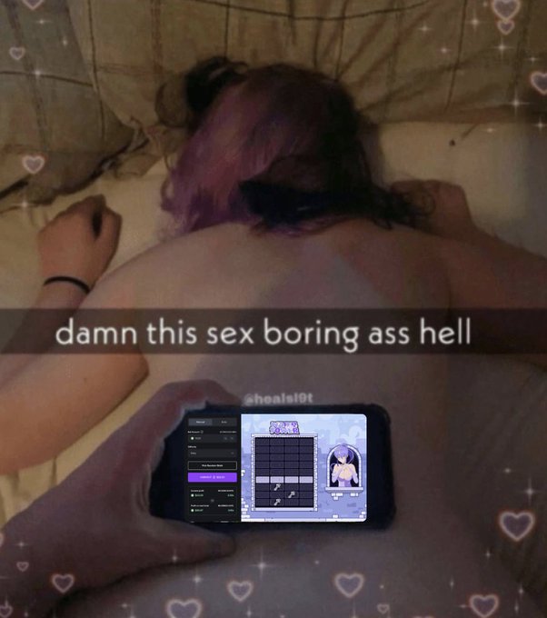 A person with pink-streaked dark hair lies face-down on a bed, playing what appears to be an anime-styled rhythm game on a smartphone, with the caption "damn this sex boring ass hell" overlaid in white text amid a sparkling heart border effect.