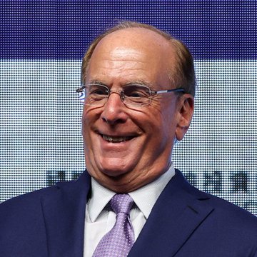 Larry Fink, CEO of BlackRock, smiles while speaking at an event. The image relates to the post as BlackRock, the asset management giant he leads, has reportedly sold another $212.45 million worth of Bitcoin.