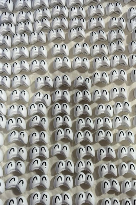 A repeating pattern of white earbuds arranged in a grid formation against a light background.