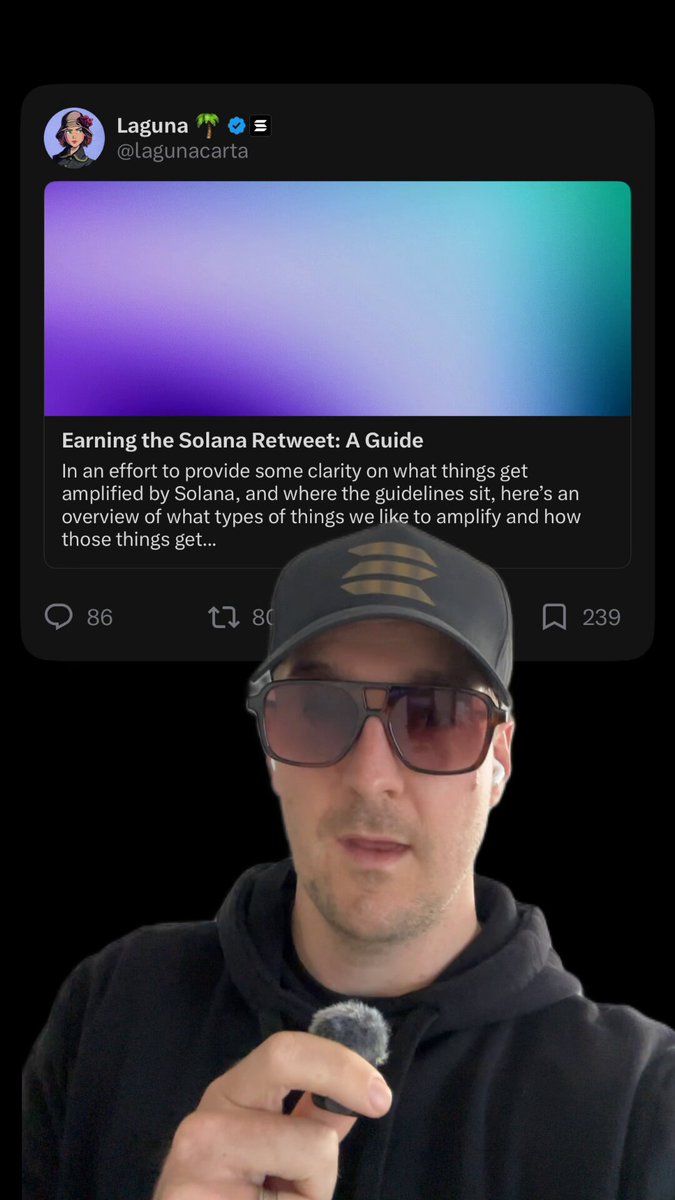 The image features a man wearing sunglasses, a black baseball cap, and a hoodie with his hand over his mouth while holding a microphone. The background of the image shows a purple and blue gradient screen displaying text that reads "Earning the Solana Between: A Guide". This suggests that the man is being interviewed or featured on this post about Solana, possibly for a social media account or blog.