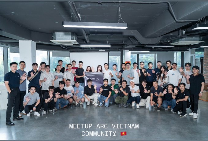 The Arc Vietnam Community held its inaugural meetup, bringing together a large group of attendees for a group photo in a modern, industrial-style venue with exposed ceiling pipes and large windows. The image features a banner reading "ARC Meetup" and includes a Vietnamese flag alongside the caption "MEETUP ARC VIETNAM COMMUNITY," reflecting the post's description of an event focused on stablecoin payments and Arc infrastructure insights.