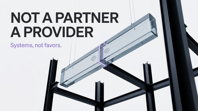 The image features a transparent, crystal-like rectangular block suspended within a black metal framework, accompanied by the bold text "NOT A PARTNER A PROVIDER" and the tagline "Systems, not favors." The visual reinforces the post's message by symbolizing how the company's blockchain infrastructure (Lotte's NFT mainnet and AhnLab's ABC Wallet) is structurally embedded—rather than loosely partnered—delivering conglomerate-grade systems backed by legal exclusivity.