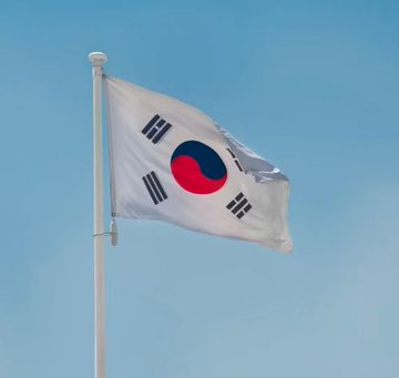 The South Korean flag (Taegukgi) waving against a blue sky.