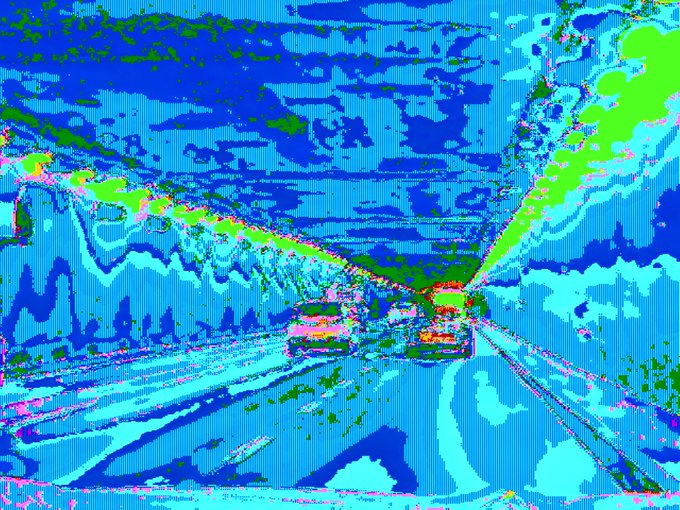 A heavily pixelated, glitch-style image dominated by blue tones with green and red accents, appearing to show a vehicle or scene through heavy digital distortion.