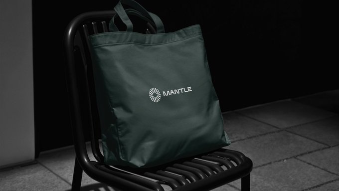 A dark green tote bag with the "MANTLE" logo rests on a black chair against a dark background, visually reinforcing the caption's message of "Borderless access, in the bag." The image suggests portability and convenience, portraying Mantle's offerings as something easily carried and ready for use anywhere.