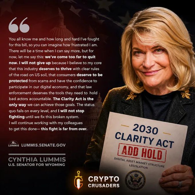 A political graphic featuring Senator Cynthia Lummis holding a '2030 Clarity Act' paper marked 'ADD HOLD', with a quote about her commitment to digital asset market structure legislation and the 'Crypto Crusaders' logo.