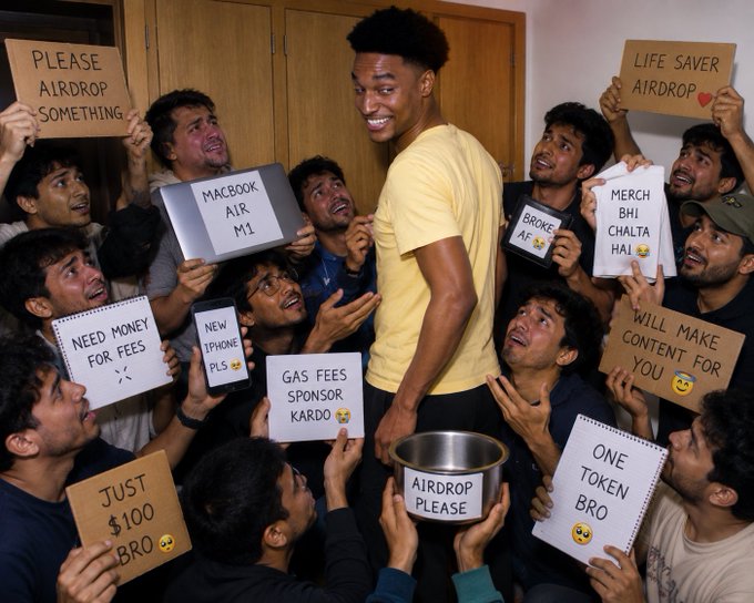 A meme image showing a crowd of people holding signs requesting crypto airdrops, including phrases like 'PLEASE AIRDROP SOMETHING,' 'LIFE SAVER AIRDROP,' 'MACBOOK AIR M1,' 'NEW IPHONE PLS,' 'GAS FEES SPONSOR KARDO,' 'JUST $100 BRO,' 'ONE TOKEN BRO,' 'WILL MAKE CONTENT YOU FOR,' and 'MERCH BHI CHALTA HAI.'