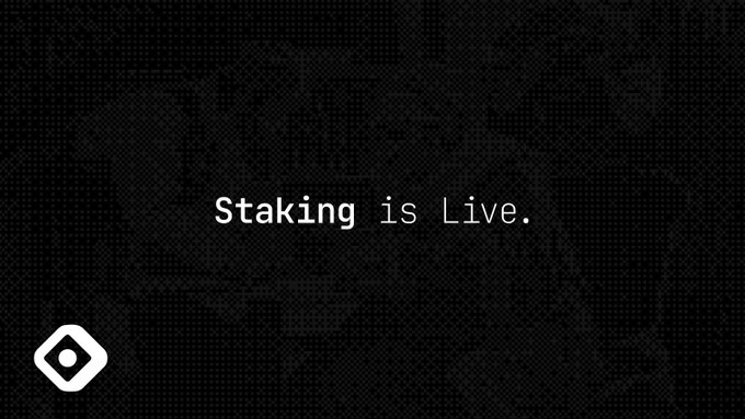 Dark textured graphic with text 'Staking is Live.' and a white logo in the bottom left corner.