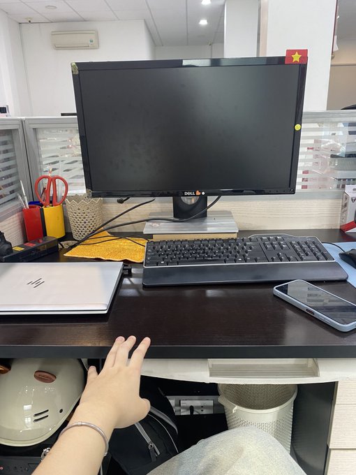 A person sits at a Dell monitor desk setup with a keyboard, phone, and notebook, wearing a bracelet on their wrist while gesturing toward the workspace. The image relates to the post's casual, resigned tone about stepping away from web3, as the empty desk suggests a transition or break from work.