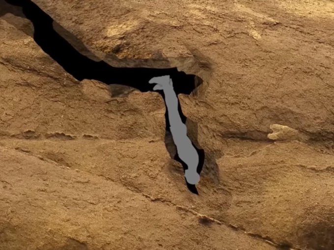Aerial view of rocky terrain featuring a white animal figure shape forming within a crack in the stone.
