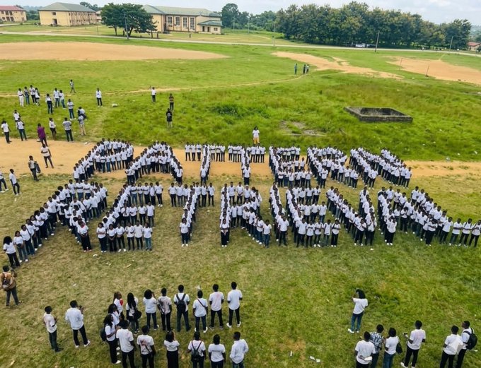 The image shows a large group of people standing together, forming the word "Pattern Retrieval" with their hands. The crowd consists of individuals wearing white shirts, indicating that they might be part of an event or gathering related to pattern retrieval. The photo is taken from an aerial perspective, providing a unique view of this collective action.