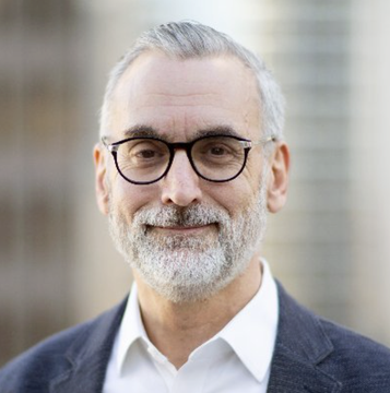 The image shows a professional headshot of a man with gray hair and beard, wearing glasses, a white shirt, and a dark blazer, set against a blurred outdoor background. The caption likely accompanies a news post about Stuart Alderoty, Ripple's Chief Legal Officer, discussing the CLARITY Act's consumer protection, AML, and KYC provisions, reflecting his role as a key legal voice in crypto regulatory matters.
