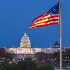 The U.S. Capitol dome is illuminated at dusk with a large American flag in the foreground, symbolizing the federal government's recent transfer of $470M in BTC, WBTC, and USDT to Coinbase Prime addresses, including seized crypto assets.