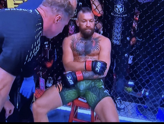 Conor McGregor sits shirtless against the UFC cage with his arms crossed, while a cornerman leans in to attend to him, evoking a smug "told you so" expression that mirrors the post's confident rebuttal to MSTR and Bitcoin skeptics.