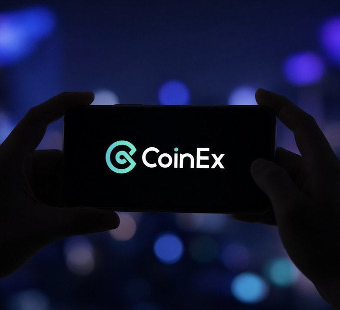 Silhouetted hands holding a smartphone displaying the 'CoinEx' logo against a dark, blurred background of blue and purple bokeh lights.