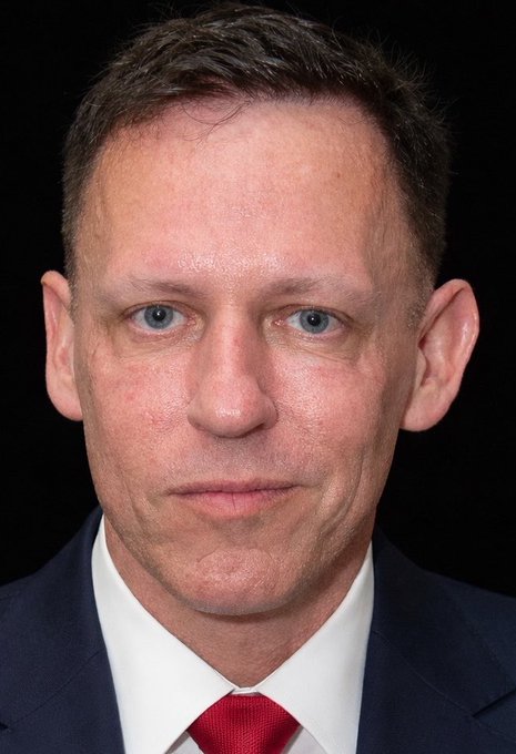 I can see a man with short brown hair and blue eyes, wearing a dark suit, white shirt, and red tie, photographed against a black background in a formal portrait style. I'm not able to identify who this person is based on their appearance. 

If you could tell me who this is, I'd be happy to help describe how the image relates to the "digital epstein" reference. Is this an official portrait of a public figure whose identity I should know in context?