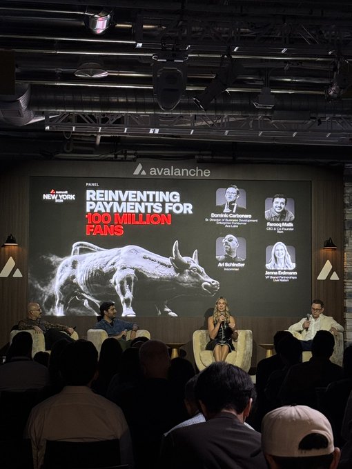 A panel discussion stage with four people seated, featuring a large screen displaying 'REINVENTING PAYMENTS FOR 100 MILLION FANS' with an Avalanche logo and a bull image, and the Movers & Shakers logo.