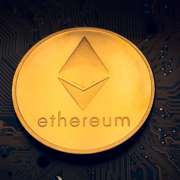 A gold-colored physical coin featuring the Ethereum logo and the word "ethereum" rests on a dark circuit board, visually representing the cryptocurrency's digital technology. The image directly illustrates the article about analysts raising Ethereum's ranking by 34 places, symbolizing its prominence in the crypto space.