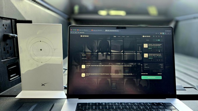 A SpaceX Starlink router sits next to an open MacBook displaying the Starlink management dashboard on its screen.