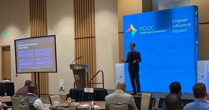 A presenter speaks on stage at the MD|DC Credit Union Association's "Engage Influence Impact" conference, with a slide titled "WHERE BLOCKCHAIN FINANCE STANDS TODAY" displaying statistics (43% and 25%) for 2020 and 2023. The image captures the conference setting referenced in the post, where discussions about digital assets and credit unions are taking place.
