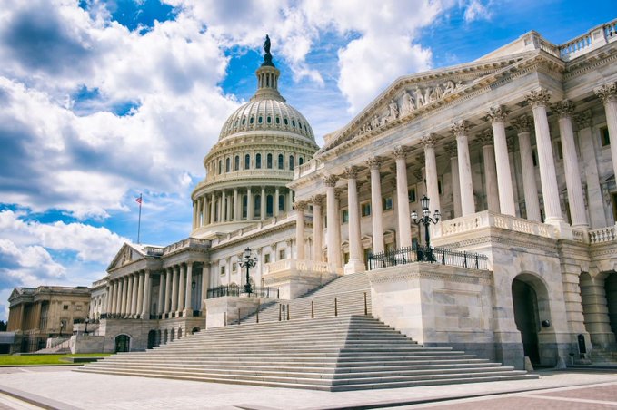 The United States Capitol Building in Washington D.C. photographed on a partly cloudy day, showing its iconic white dome and grand columned facade with stone steps leading up to it.