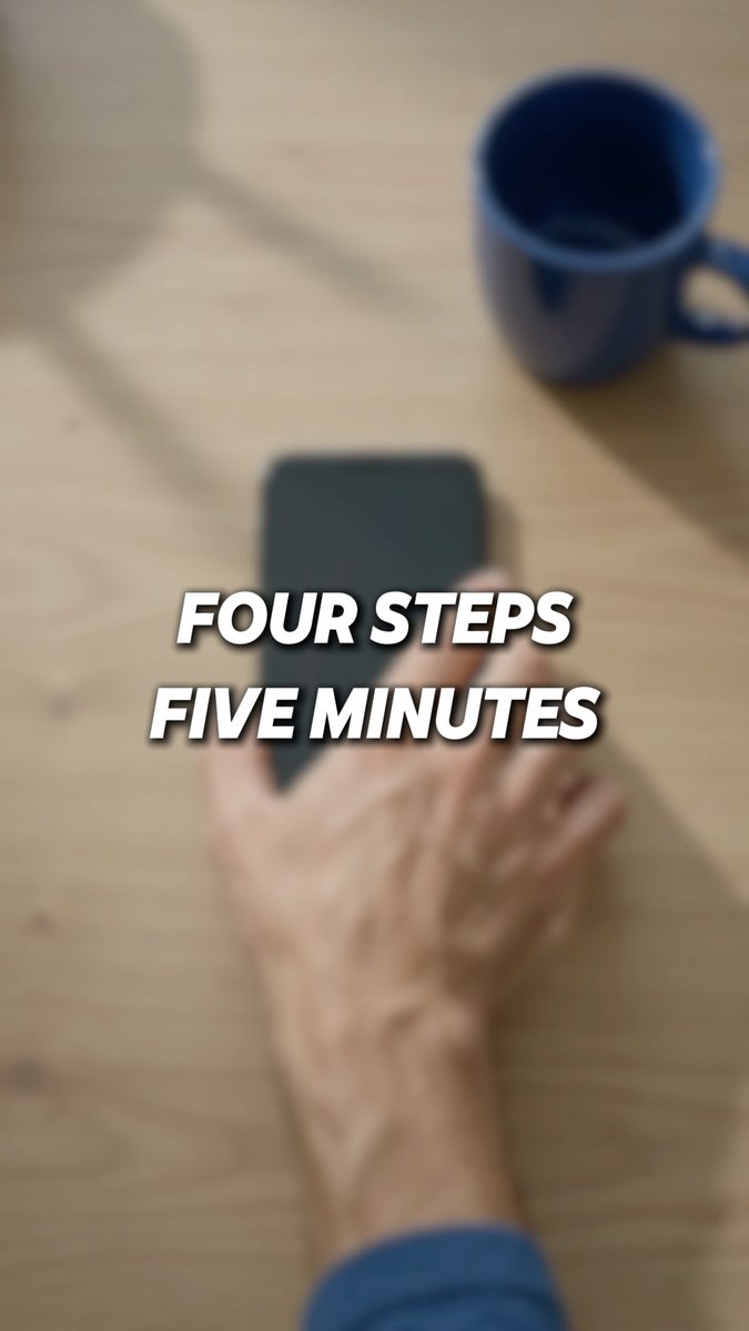 A blurry top-down view shows a hand holding a smartphone next to a blue coffee mug on a wooden table, with the overlaid text 'FOUR STEPS FIVE MINUTES'.