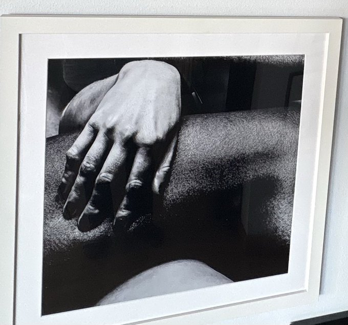A framed black-and-white photograph showing a hand resting on textured fabric.