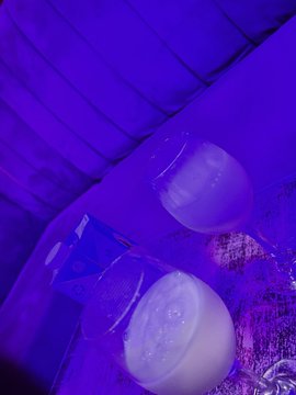 A dimly lit photo taken at an event bathed in purple and blue lighting, showing translucent plastic containers or bowls on a surface.