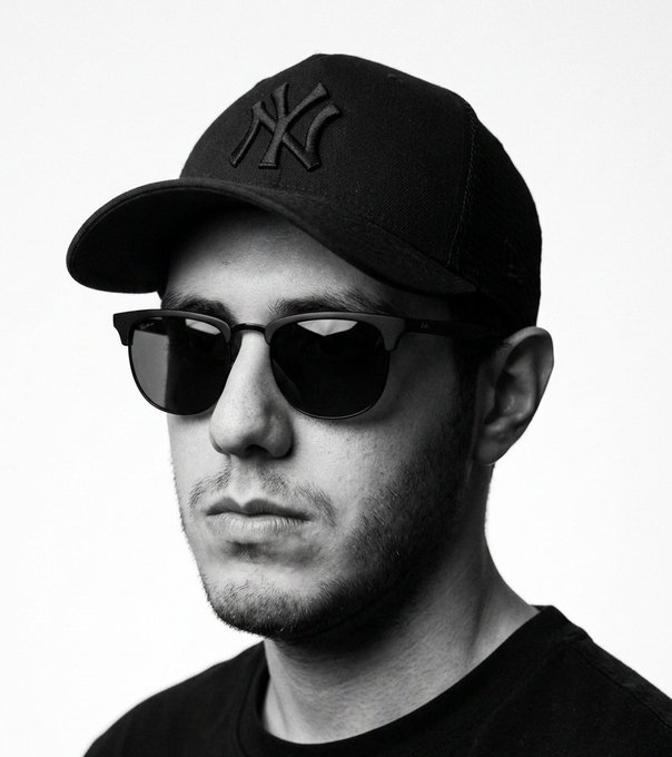 A black-and-white portrait shows a man wearing a black New York Yankees cap featuring the iconic interlocking "NY" logo, along with dark sunglasses and a black t-shirt, presenting a new, more low-key profile look that aligns with his transition away from using NFTs as his social media picture.