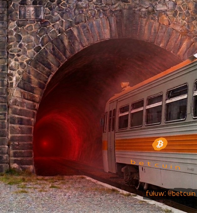 An image showing a train labeled 'betcuin' with a Bitcoin logo emerging from a stone tunnel with a red glow inside, credited to '@betcuin' in the corner.