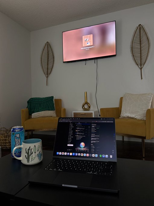 A laptop sits open on a coffee table in a cozy living room, with Siri voice assistant displayed on screen, while a wall-mounted TV in the background shows the TVOS update screen. The scene, featuring a coffee mug and beverage can alongside the devices, reflects a relaxed remote-work or tech-update moment that the poster credits Solana with enabling—likely referencing a successful transaction or recovery that allowed them this downtime.