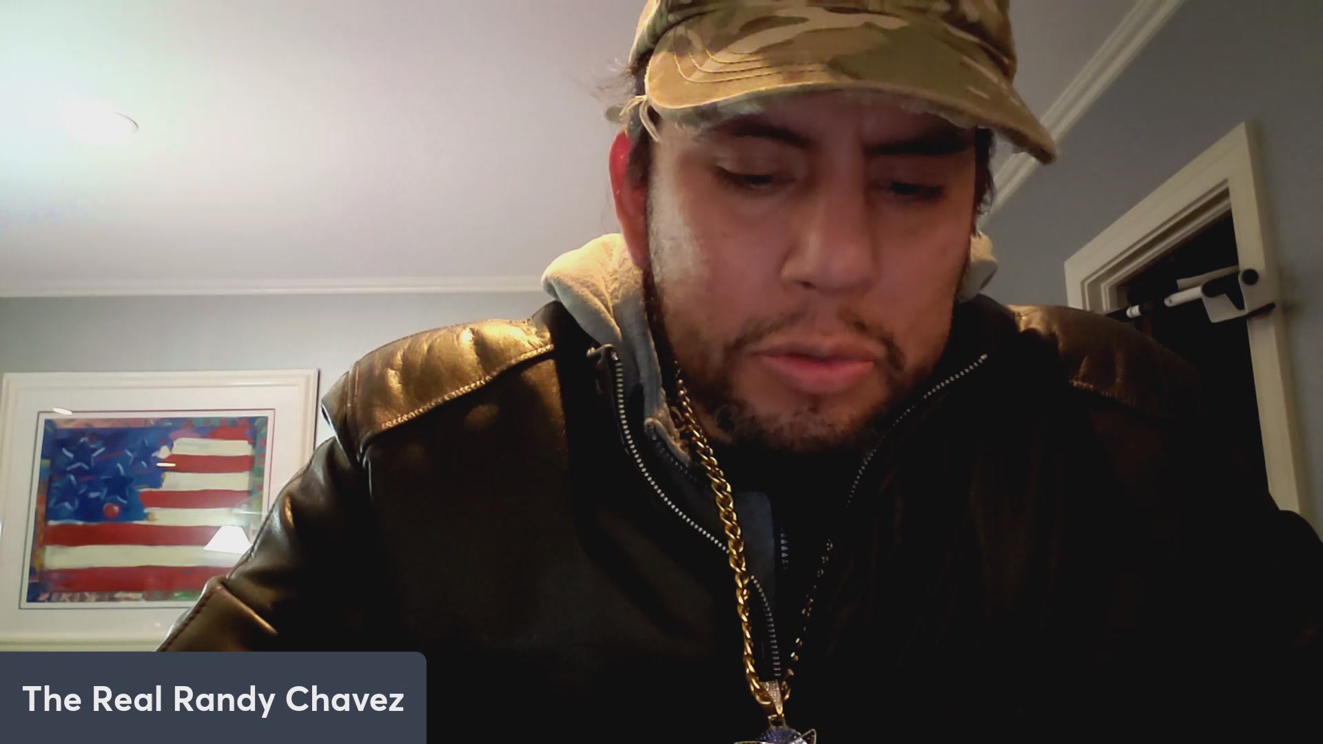 The image features a man wearing a camo hat, a leather jacket, and a gold chain necklace. He appears to be looking down at something or someone with an intense expression on his face. The caption of the image reads "VeVe averages 15k subs! Stickerverse 15k subs!". This suggests that the man might have been browsing through some content on Stickerverse, which is known for its focus on niche interests and obscure posts.