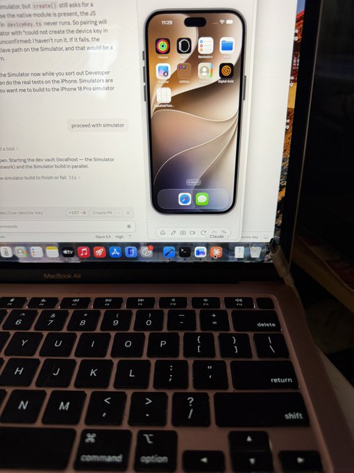 A MacBook Air laptop displays Xcode with an iOS Simulator previewing an iPhone interface, with the device's keyboard visible in the foreground.