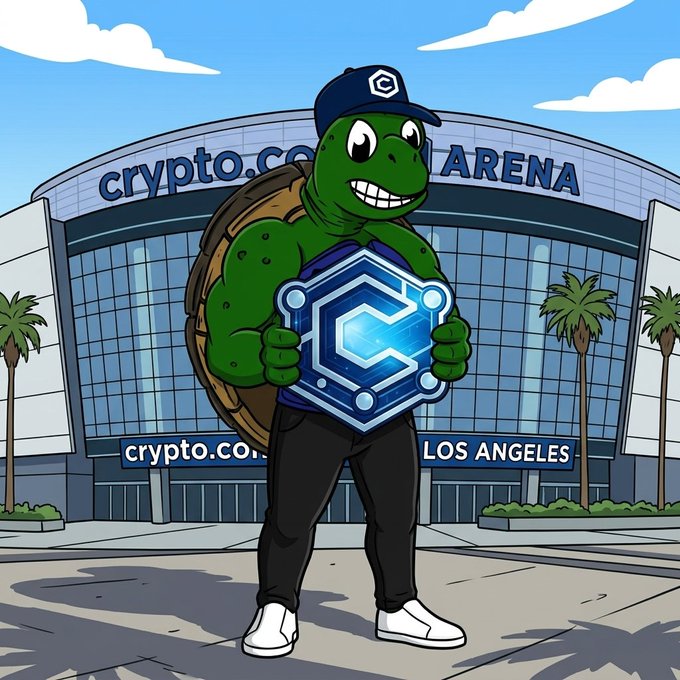 A cartoon muscular turtle mascot wearing a cap and holding a glowing hexagonal Crypto.com logo stands in front of the Crypto.com Arena in Los Angeles.