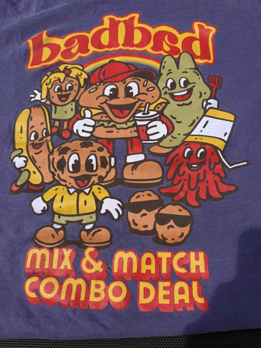 The image features a purple t-shirt with a cartoon design depicting various food items, including a hot dog, hamburger, and donut. The text "Badbed" is written above the cartoon characters, while "Mix & Match Combo Deal" is below them. The t-shirt has a hole in it, which might have been caused by a sneaker or an accidental tear.