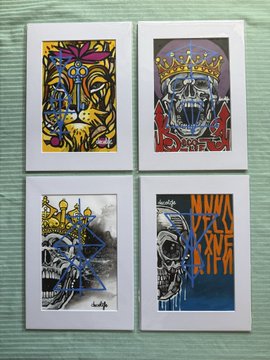 Four colorful skull-themed art prints are arranged in a 2x2 grid on a white mat, featuring bold graffiti-style designs—one includes the text "MANUFACTURED IN NEW YORK CITY." The artwork showcases the edgy, street-art aesthetic that connects to the artist's work (decolife1) recently acquired by the collector.