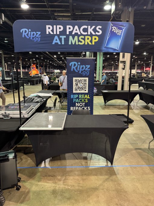 A Ripz.gg booth at a trade show with banners reading 'RIP PACKS AT MSRP' and 'RIP REAL PACKS NOT REPACKS' alongside a QR code, with various cases and equipment on display tables.