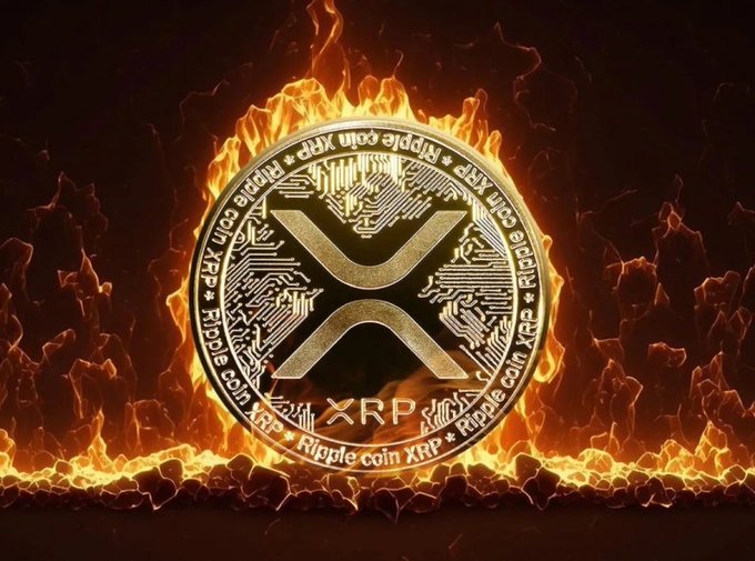 A dramatic digital artwork featuring an XRP (Ripple coin) cryptocurrency coin surrounded by intense flames against a dark, mountainous background. The coin prominently displays the XRP 'X' logo with 'Ripple coin XRP' text around its circuit-board designed border.