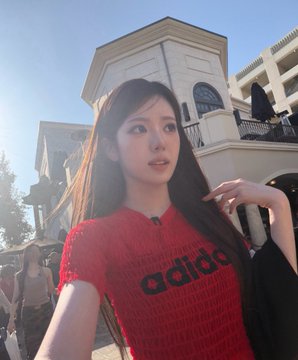 A young woman with long dark hair wearing a red "adidas" mesh top takes a selfie outside in front of white colonial buildings under bright sunlight. The "260817 bubble #Sui" post likely references the photo's timestamp and a personal caption, with the bubble text possibly relating to the airy mesh material of her shirt.