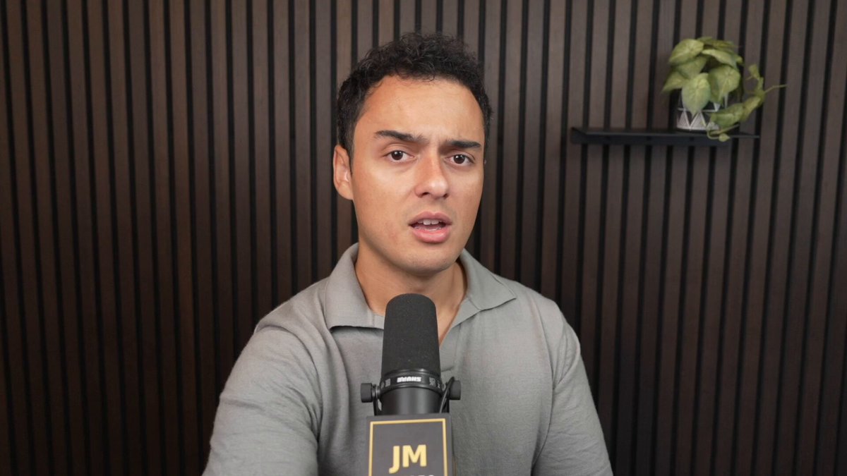 urn of green plant on shelf, brown wall with vertical lines, microphone and speaker, man's face in profile, "JM" logo.