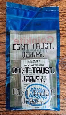A small blue resealable mylar bag containing a product card that prominently reads 'DON'T TRUST. VERIFY.' in repeated text.