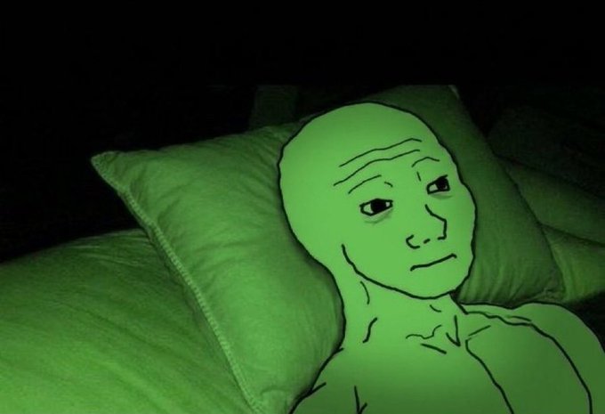 A green-tinted internet meme showing a simple line-drawn 'wojak' face with a sad expression superimposed over a person lying in bed on a pillow.