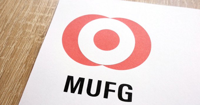 The image shows the red-and-black “MUFG” logo on a document. It relates to a report that MUFG will use blockchain technology for instant settlement of government bond repurchase transactions, targeted for fiscal 2027.