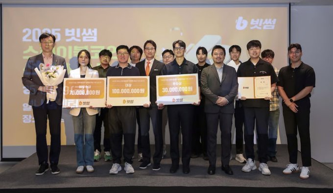 A group of individuals poses together at the "2025 빗썸" (Bithumb 2025) awards ceremony, holding oversized checks displaying prize amounts of 75,000,000 won, 100,000,000 won, and 30,000,000 won, alongside certificates. The image aligns with the post's theme of professional accomplishment and recognition, likely showcasing a milestone moment that reinforces the author's reflection on past achievements while looking toward future growth.