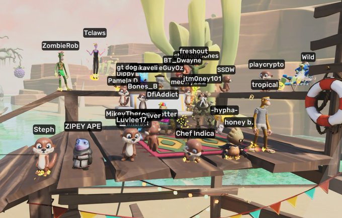 A screenshot from a virtual game showing various animated characters with usernames like 'Tclaws', 'ZombieRob', 'playcrypto', 'Steph', 'Chef Indica', and 'MikeyTheTrickster' standing on a wooden platform in a desert-like setting.