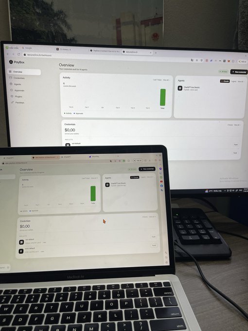 A laptop and external monitor both display the PlayBox Overview dashboard showing $0.00 in credits and recent platform activity, while a sleepy user waits in the middle of the night for a MoonPay airdrop. The image captures the late-night exhaustion of someone passively monitoring their crypto rewards.