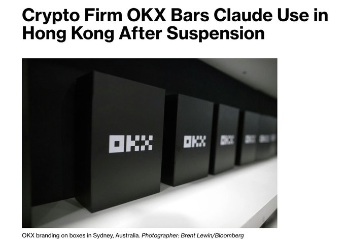 The image depicts OKX branded boxes displayed at their Sydney, Australia office, with a headline announcing that crypto firm OKX has banned its Hong Kong employees from using Anthropic's Claude following a brief suspension of their enterprise account. The photo visually anchors the article by showing OKX's corporate branding, while the text reveals the company restricts Claude access regionally amid spending $6–8 million monthly on AI models.