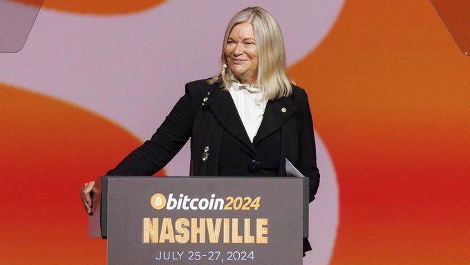 A blonde woman speaks at a podium labeled “bitcoin2024 NASHVILLE” and “JULY 25–27, 2024.”
