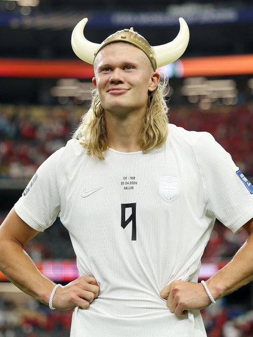 Erling Haaland smiles while wearing a Viking horned helmet and a white Manchester City jersey with number 9 and the inscription 'GW - NSR 30.04.2026 MILAN' after a match.